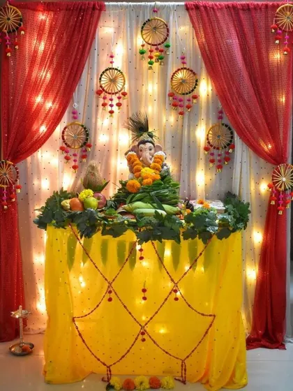 A traditional decoration using red and yellow fabrics with dreamcatcher-style hangings. The fairy lights in the background add a warm and festive glow.