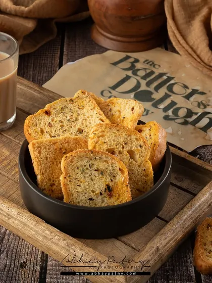 This shot of tea rusks is styled to evoke a sense of nostalgia and comfort. The wooden tray and a classic glass of chai create a perfect teatime scene.