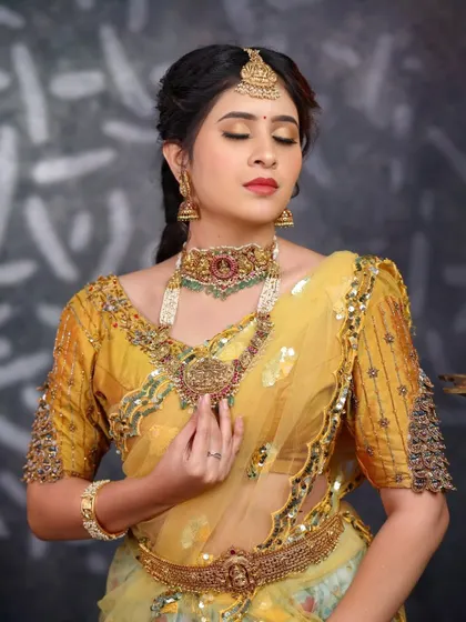 A moment of quiet beauty. This bride is adorned in a detailed temple jewellery set, featuring a choker and a longer necklace with a central goddess motif.