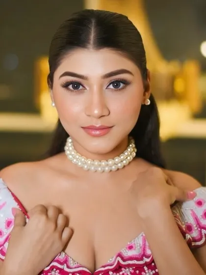 A glamorous, glassy makeup look with a pop of pink. The off-shoulder blouse and pearl choker add a modern, chic touch to this festive style.