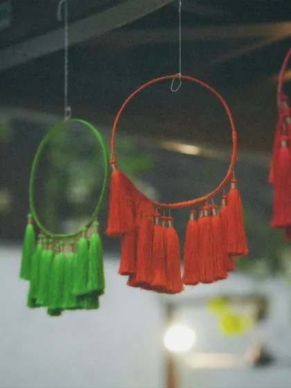 A close-up of colorful tassel dreamcatchers used as hanging decor. These handmade details add a bohemian and whimsical touch to the mehendi celebration.