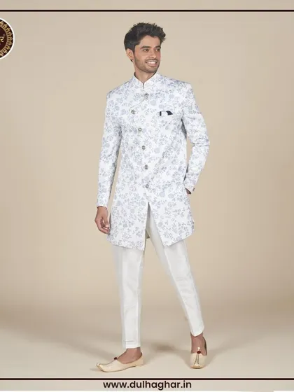A full-length view of a white floral printed Indo-Western jacket paired with white trousers and traditional juttis.