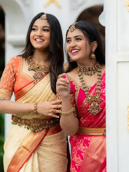 Two models showcasing complementary South Indian bridal looks. It gives a great idea of how bridesmaids or sisters can coordinate their jewellery for a wedding.
