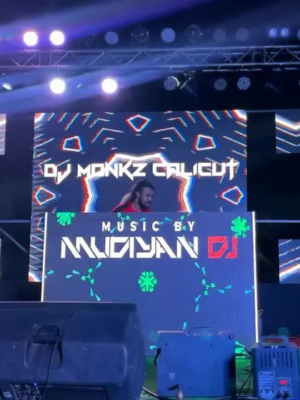 A view of my DJ setup with a large LED screen behind me, displaying my name and graphics from DJ Monkz Calicut.