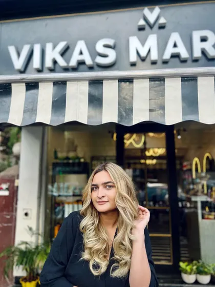 The client posing outside the salon with her new blonde hair. The color looks incredible in the natural sunlight.