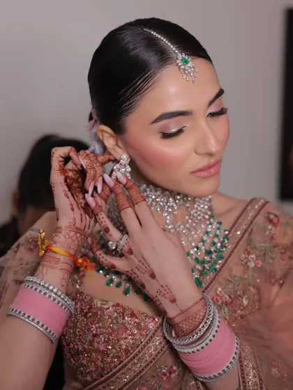 It's these quiet, in-between moments that are pure magic. Here, we see the final touches coming together: the soft pink eyeshadow, the glowing skin, and the intricate diamond and emerald jewelry. This is a perfect example of a soft glam bridal makeup look.