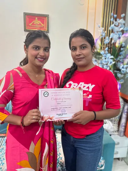 A happy student holding her certificate of training after completing the professional nail art course.