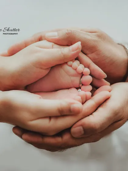 The whole family's hands together, cradling the baby's tiny feet. This portrait is a beautiful representation of family unity and love.