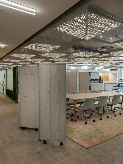 A "Tech Connect" zone in a modern office, designed as a hub for innovation. The space features a living green wall, flexible meeting tables, and lockers, supporting an agile and technology-driven work culture.