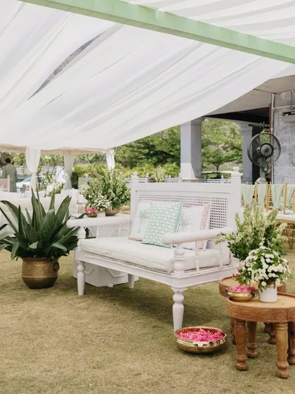 Another view of the Mehendi lounge area, where white furniture and lush green plants create a fresh and serene atmosphere.