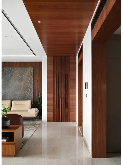 The main corridor features a continuous wooden ceiling and paneling that conceals a traditional temple. This allows for a seamless transition between the contemporary living spaces and the sacred puja area.