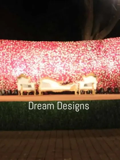 A truly grand statement stage featuring a massive wall of pink and white flowers. The sheer scale of the floral backdrop creates an impactful and luxurious setting for a large reception.