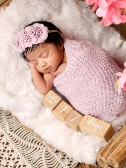 This 17-day-old newborn is beautifully wrapped in pink and resting in a basket. The flowers add a soft, delicate touch to this classic newborn portrait.