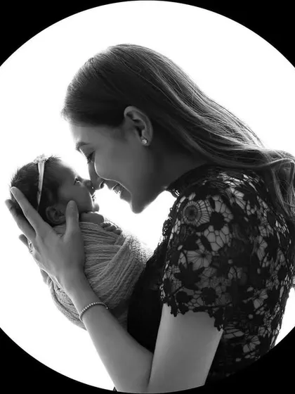 A timeless black and white silhouette of a mother and her newborn twin. The circular frame focuses all attention on their nose-to-nose connection.