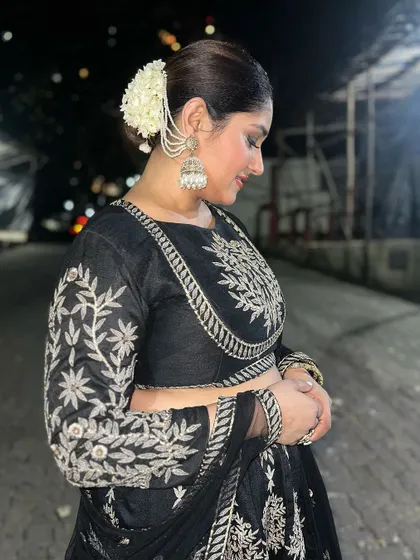 A side profile of Donam Bajwa, highlighting her elegant bun with a gajra and the detailed embroidery on her rented festive outfit.