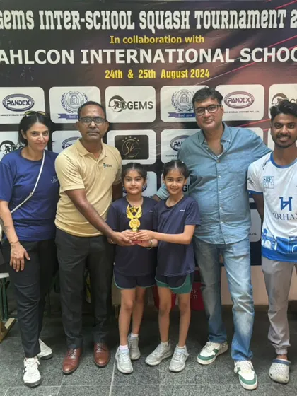Presenting a trophy to young winners at the GGems Inter-School Tournament, flanked by proud parents and coaches.