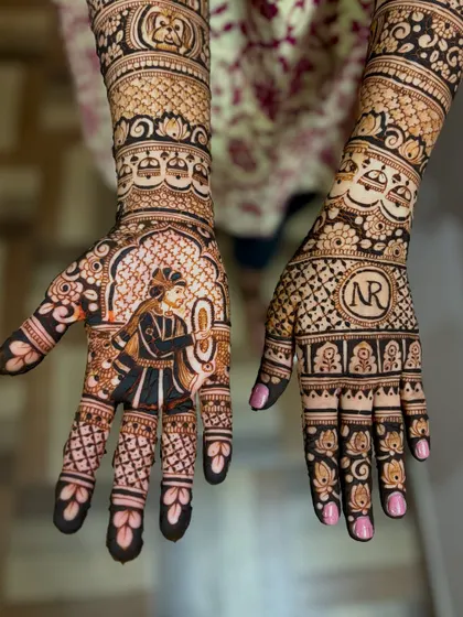 A closer look at the individual palms. One hand features the groom's portrait, while the other has the couple's initials, "NR," inside a beautifully decorated circle.