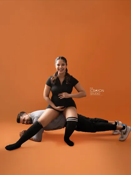 A playful and strong pose, with her sitting on his back as he holds a plank. This couple's fun personality shines through in their creative maternity shoot.