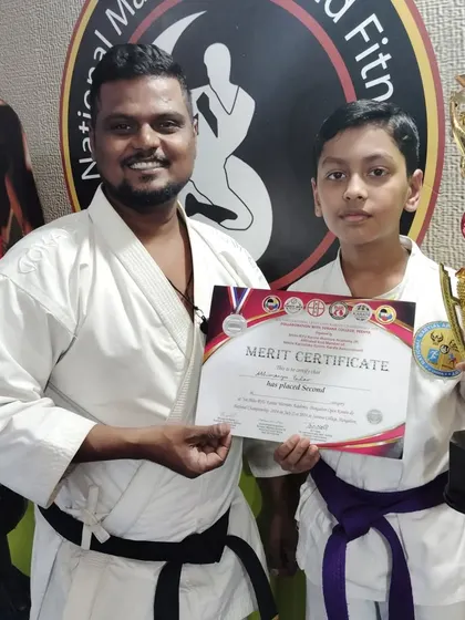 A second-place achievement for this purple belt student, holding his certificate and trophy with pride.