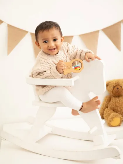 A classic first birthday portrait with a rocking horse. This setup has a rustic, charming feel with the burlap banner and wooden toys.