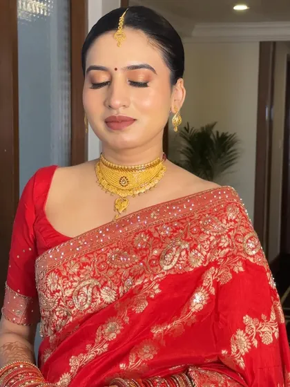 A close-up of Damini's serene wedding day makeup. The soft brown and gold tones on her eyes perfectly complement the gold jewelry and embroidery on her saree.