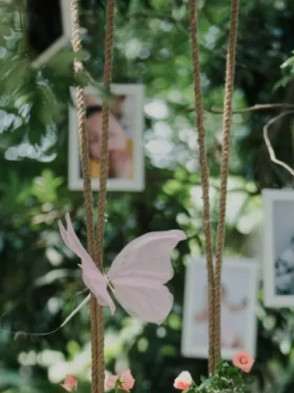 A whimsical detail from a garden party, featuring a delicate pink butterfly and hanging photo frames. These small, personalized touches help in telling the client's story.