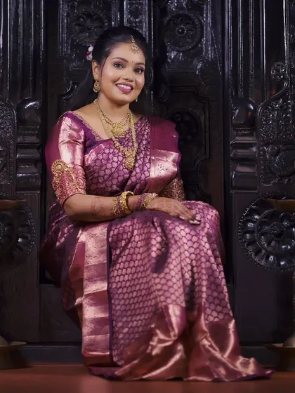A regal portrait of the bride-to-be seated on an ornate wooden chair, looking elegant in her silk saree.