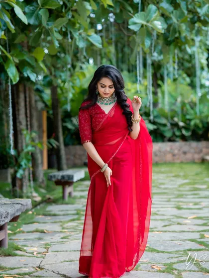 A client looking radiant in a vibrant red organza saree, paired with a beautifully embroidered blouse.