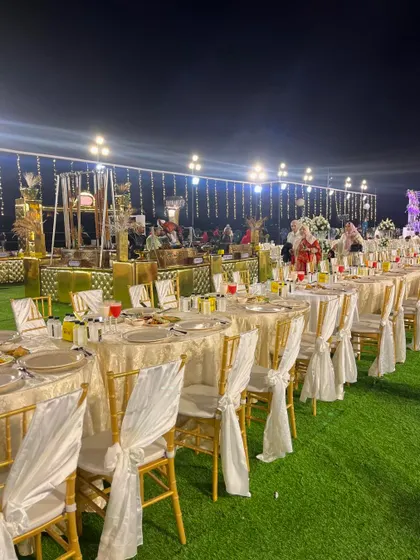 An outdoor dining area with round tables and elegant chair coverings.