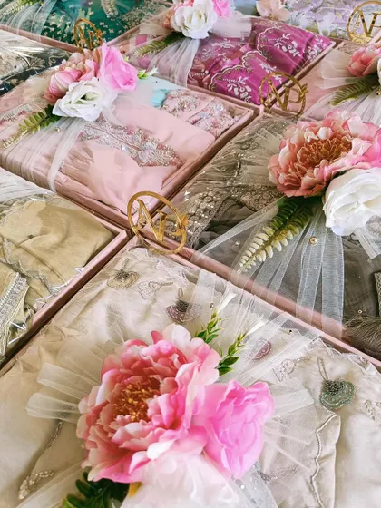 An overhead view of trousseau trays with a pastel pink and floral theme. Each tray is personalized with a golden monogram, adding a touch of bespoke luxury.