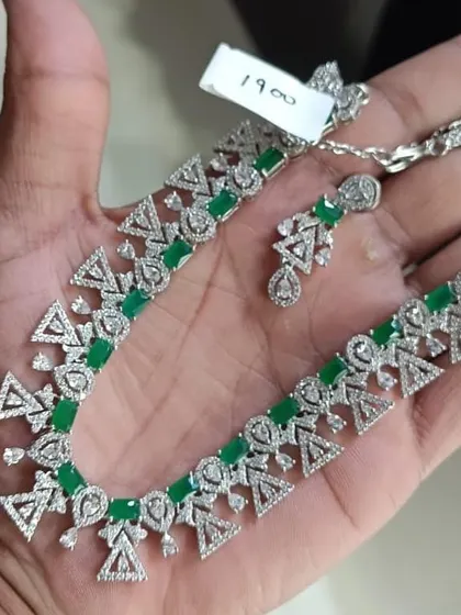 A modern and geometric American Diamond necklace with green stones. The unique triangular design sets it apart from common styles. It's a great choice for those who love contemporary jewellery.