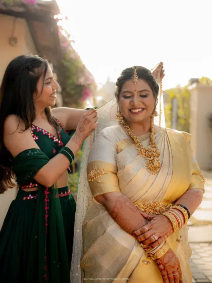 A bridesmaid helps the bride with her veil. This beautiful, sun-kissed photo captures a moment of friendship and support.
