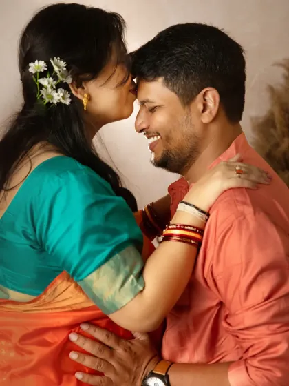A close-up of a forehead kiss, a signature shot that is full of emotion. The flowers in her hair add a delicate, natural touch to this intimate moment between the couple.