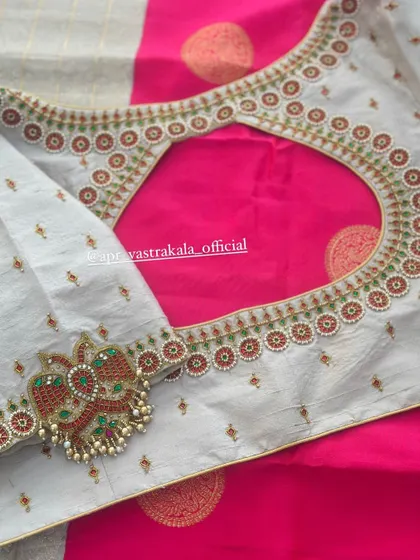 A grey blouse with a pink contrast, featuring peacock motifs on the sleeves.