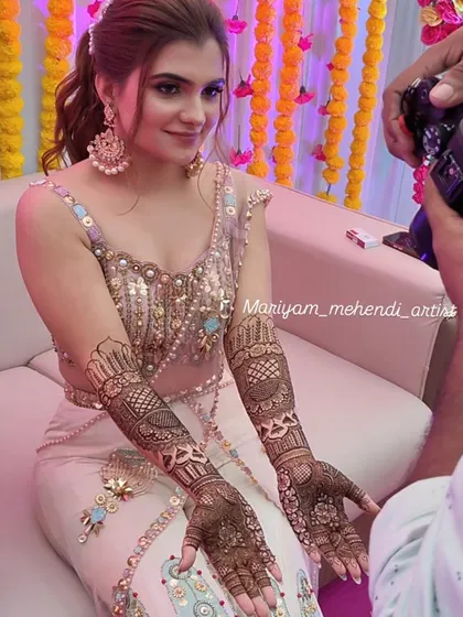 A beautiful bride showcasing her full-arm Indian bridal mehendi.