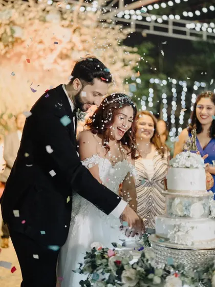 A moment of pure happiness during the cake-cutting ceremony, with confetti raining down on the laughing couple. This shot is full of life and celebration.