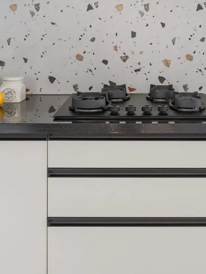 A close-up of the hob area in the white and black kitchen. The design focuses on clean lines and a minimalist aesthetic, with handleless drawers and a simple, elegant finish.