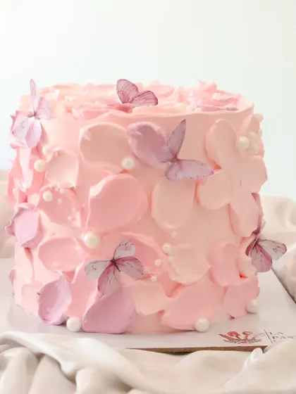 A lovely pink cake decorated with abstract petal shapes and delicate butterflies. The different shades of pink create a beautiful texture.