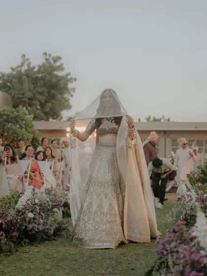 The bride's playful peek-a-boo moment during her entrance. Ishita's joyful expression as she lifts her veil to see her groom is a perfect blend of tradition and modern fun.
