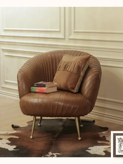 This pleated leather club chair is a study in texture and form. Placed on a genuine hide rug, its curved silhouette and delicate metal legs offer a modern take on classic comfort, making it a perfect accent for any sophisticated corner.
