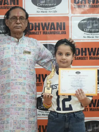 A senior guru with his young student and her award.