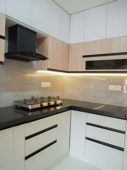 A different perspective of the two-tone kitchen, highlighting the seamless integration of the chimney and the balance of different finishes. The design is both contemporary and warm.