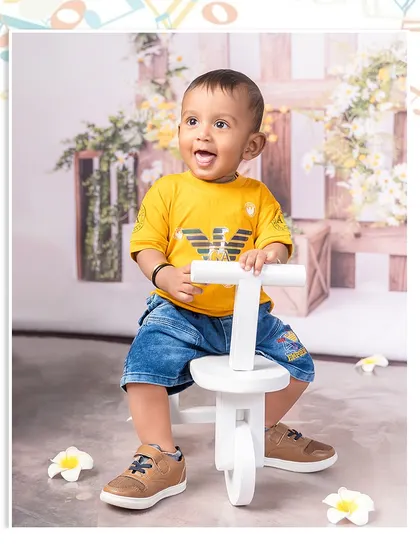 A joyful ride on a little white tricycle. This happy boy is having a blast in our rustic garden setting, a perfect picture of childhood fun.