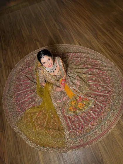 An aerial shot that captures the full circular flare of the bridal lehenga. The dupatta is draped to create a beautiful cascading effect.