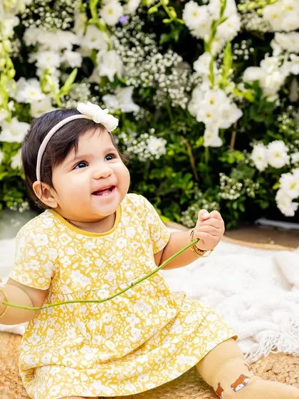 A happy baby girl in a field of flowers. The contrast in black and white makes this a striking and beautiful portrait.