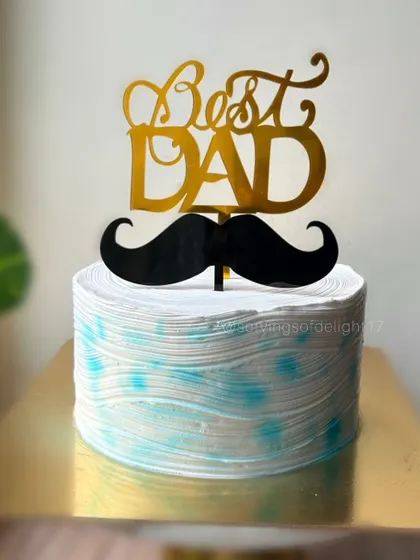 A cake for the "Best Dad," featuring a textured blue and white design and a classic mustache topper. A perfect treat for Father's Day.