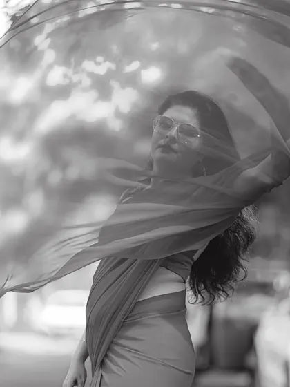 The same red georgette saree in a monochrome shot, highlighting the flow and texture of the fabric. Black and white photography often reveals the pure form of an outfit.