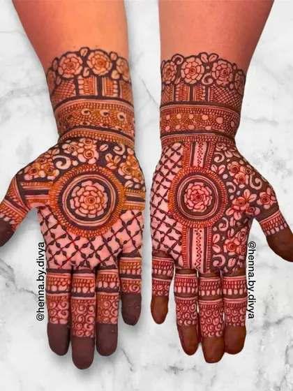 A beautiful symmetrical Indian mehendi with a central floral mandala and a grid pattern on the palms. The wrists feature a classic band of roses.