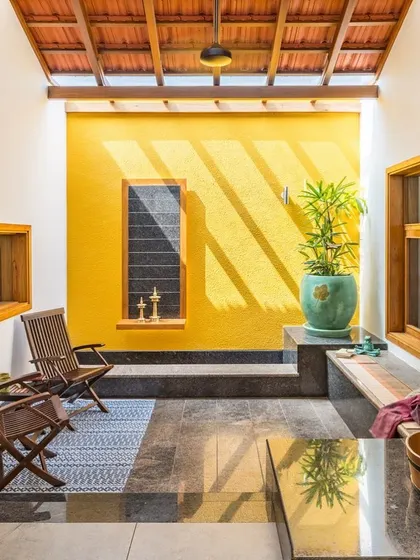 Light and color bring this semi-open space to life. The warm yellow wall catches the sunlight filtering through the tiled roof, creating beautiful, shifting shadows across the granite flooring and seating area throughout the day.