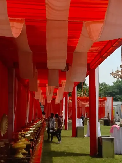 This is another view of a tented catering area I set up on a lawn. The red and white fabric canopy with a hanging chandelier provides a functional and decorative space for guests.